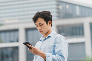 Young Asian man is standing looking at the phone
