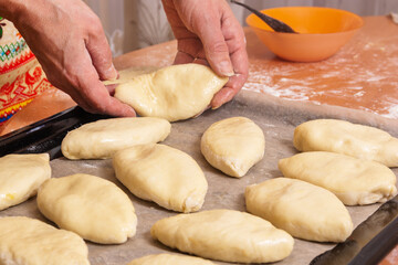 Russian pies made of raw dough prepared for baking in the oven. Homemade cakes greased with a raw egg