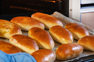 The woman pulls out ready-made Russian pies with filling from the oven. Homemade baking