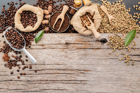 Background of various coffee , dark roasted coffee beans , ground and capsules with scoops setup on wooden background with copy space.