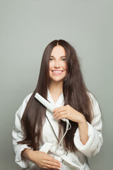 Happy woman straighten her hair on white background. Haircare concept