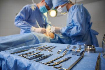 Plastic surgery instruments on surgical table with medical team and patient on blurred background....