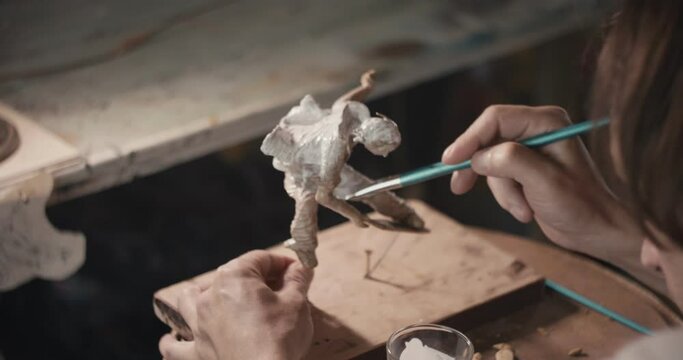 Artist apply white glaze on sculpture with hand paintbrush close up