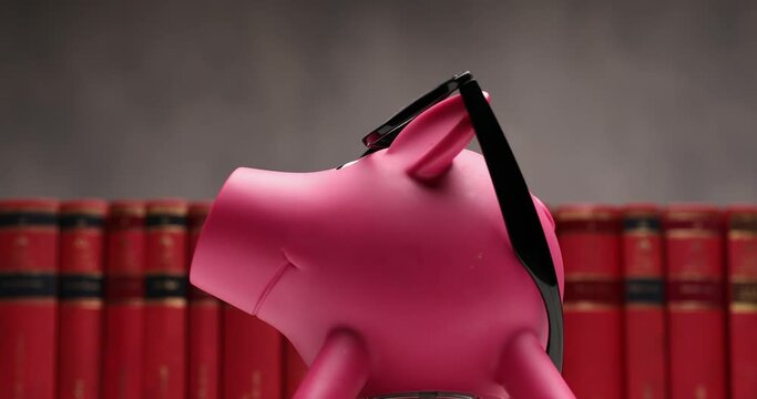 nerd piggy bank with glasses is sliding from right to left against a book row