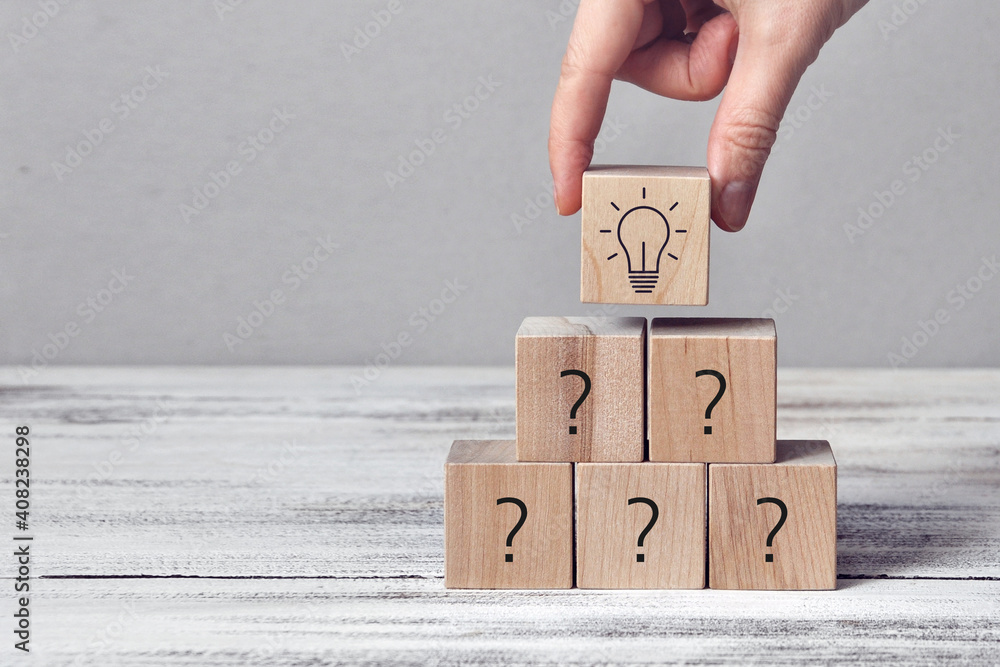 Poster wooden cubes with drawings of questions and a burning light bulb. a symbol of difficult questions an