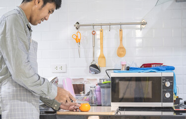 Blurred man asian cooking in kitchen of home He hands cutting vegetables and cutting fruit in the kitchen   to great hand on microwave in kitchen blurred background