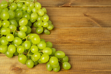 Bunch of green grapes on wooden table with space for text.