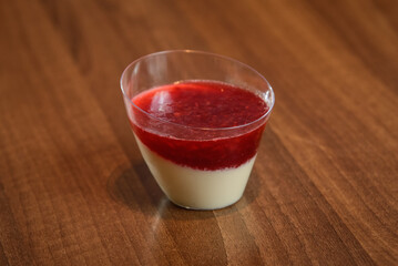 Delicious Italian dessert Panna Cotta with raspberry coulis in small transparent glasses