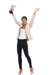 full body picture of smiling young woman holding silver trophy