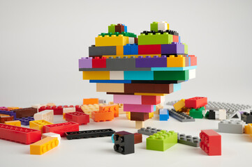 Fototapeta premium heart composed of children's blocks among scattered children's building blocks on a white background