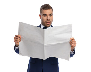 astounded young guy in navy blue suit reading newspaper