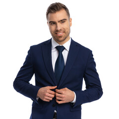 happy young businessman looking to side and unbuttoning suit