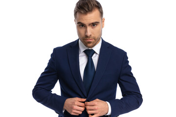 portrait of sexy elegant man arranging navy blue suit