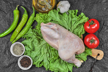 Raw chicken on wooden board with bunch of fresh vegetables and spices