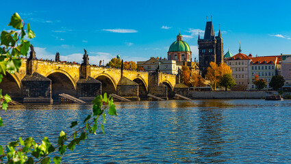 Fototapeta na wymiar Scenic view of autumn Prague cityscape and ancient stone Charles Bridge across Vltava River on sunny day, Czech Republic