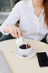 A woman with a cup of coffee in a summer outdoor cafe