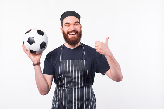 Photo of chef man holding soccer ball and showing thumb up.