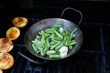 Bohnen in einer stahlpfanne auf dem gasgrill
