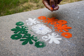 Female making rangoli design of tricolored design saffron white and green on occasion of Indian...