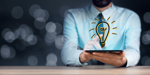 hands using tablet and bulb hologram