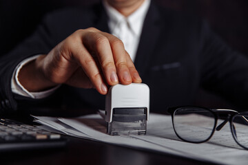 Close-up of businessman putting stamp on documents in the office. Business concept.
