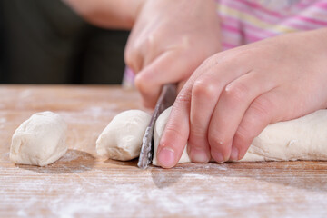 Cut the dough for the homemade pasta. Woman cuts the dough with a knife on wooden table