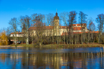 View of historic fortified Nesvizh Castle, landscape park and ponds on sunny winter day, Belarus