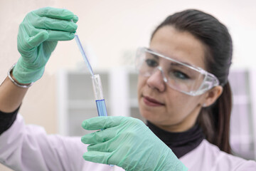 A female scientist in the laboratory examines a vaccine in a test tube. Creating a vaccine in the laboratory.