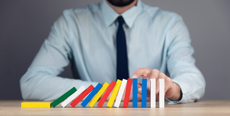 Business man stopping domino effect