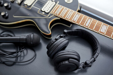leisure, music and musical instruments concept - close up of bass guitar, microphone and headphones on black table