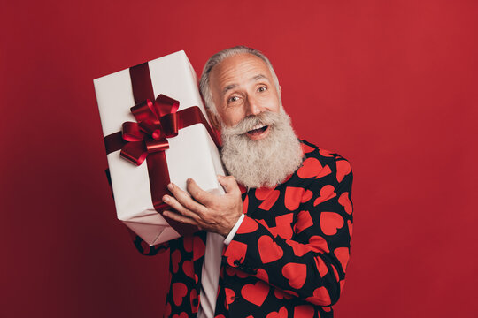 Photo Of Excited Crazy Old Man Hold Present Box Guess Open Mouth Wear Tuxedo Isolated Red Background