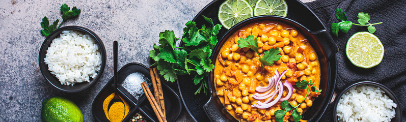 Vegan chickpea curry with rice and cilantro in black plate, dark background. Indian cuisine concept. - obrazy, fototapety, plakaty