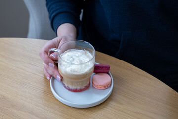A person sitting at a table with a cup of coffee.a cup of coffee in a woman's hands. Top view. High quality photo