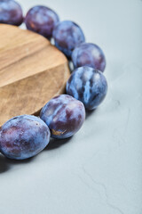 Group of fresh plums around the wooden plate
