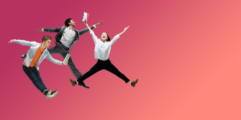 Fototapeta na wymiar Happiness. Happy office workers jumping and dancing in casual clothes or suit isolated on gradient neon fluid background. Business, start-up, working open-space, motion, action concept. Creative