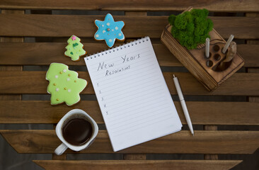 Naklejka na ściany i meble A notebook with plans for the new year, around the notebook are cookies in the form of Christmas trees and a cup of coffee