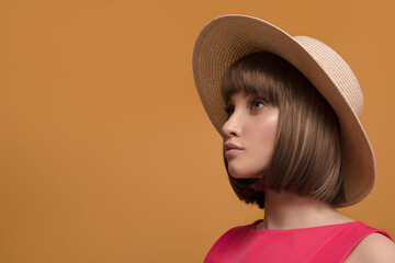 Portrait of a beautiful brown-haired woman in a hat on a yellow background.