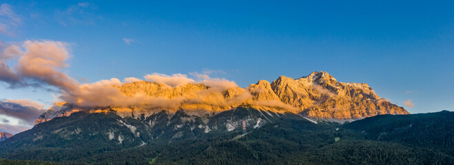 Panoramic aerial view of Alpenglow Zugspitze with fog by Eibsee lake in Germany sunset