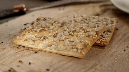Closeup of falling sesame seeds on just baked cracker with sunflower and sesame seeds. Vegetarian snacks for a healthy lifestyle without gluten. Homemade crunchy organic cookie. - Powered by Adobe