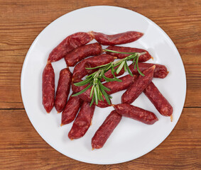 Small thin dry cured sausages on a dish, top view