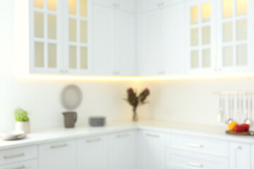 Fototapeta na wymiar Blurred view of modern kitchen interior with white furniture
