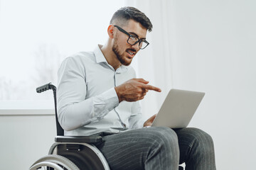 Businessman sitting in wheelchair and using laptop