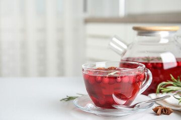 Tasty hot cranberry tea in glass cup on white table. Space for text