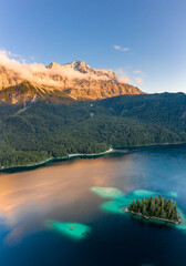 Aerial drone shot of Alpenglow with fog on Zugspitze by Eibsee lake in Germany