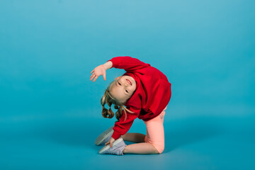 Beautiful girl sits on a splits isolated on a blue background