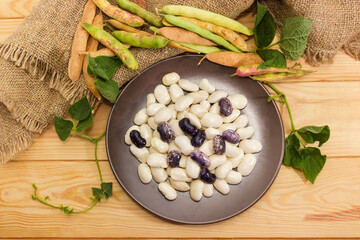 White and purple beans on dish, bean pods, top view