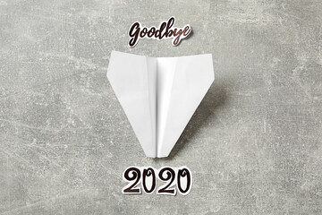 Text Goodbye 2020 and paper plane on grey background, flat lay