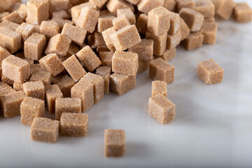 Brown sugar cubes. Natural brown sugar cubes on white marble surface.