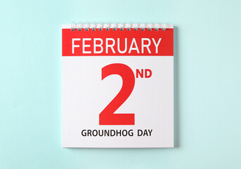 Top view of calendar with date February 2nd on light blue background. Groundhog day