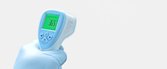 Gloved  hand holding a digital body temperature detection device. Panoramic image with copy space. 